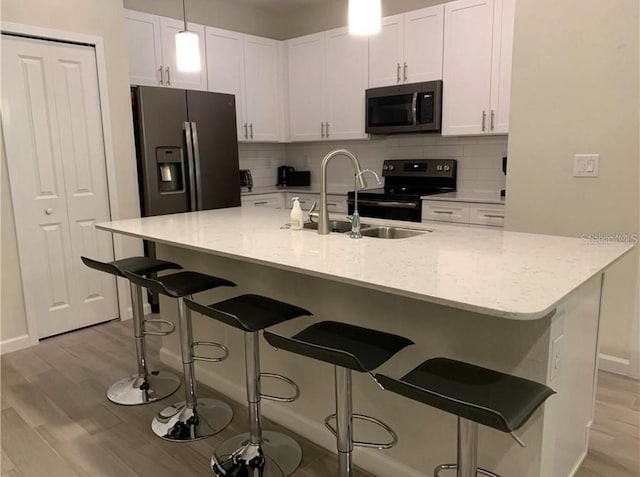 kitchen with a breakfast bar area, backsplash, white cabinetry, and stainless steel appliances