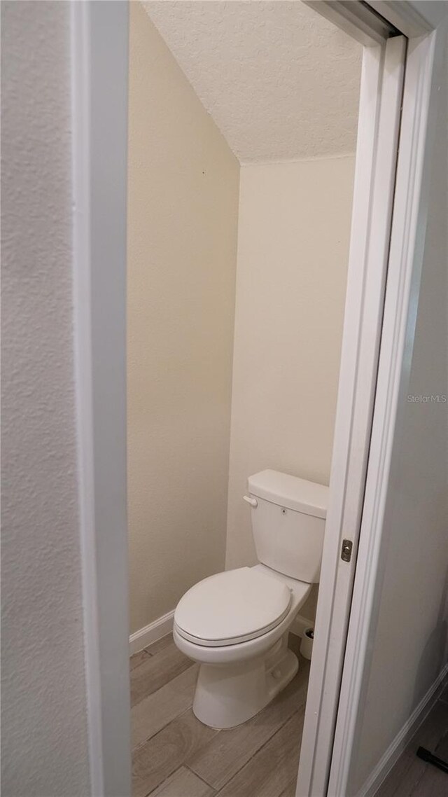 bathroom with hardwood / wood-style flooring, toilet, and a textured ceiling