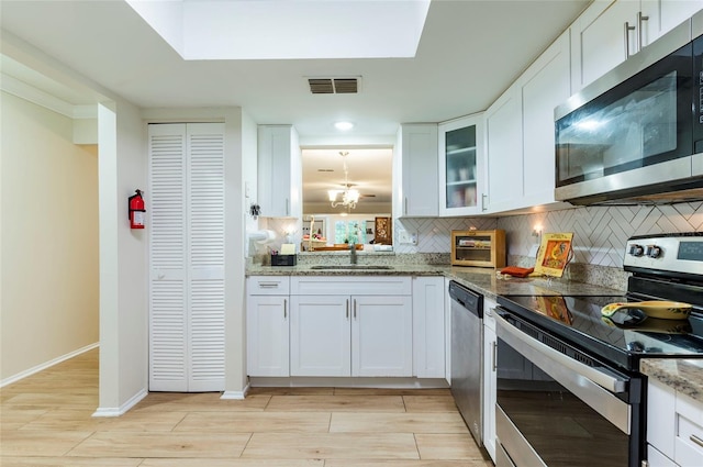 kitchen featuring stainless steel appliances, white cabinetry, sink, light stone countertops, and decorative backsplash