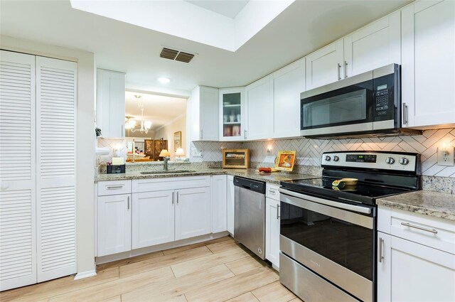 kitchen featuring white cabinetry, sink, appliances with stainless steel finishes, light stone countertops, and backsplash