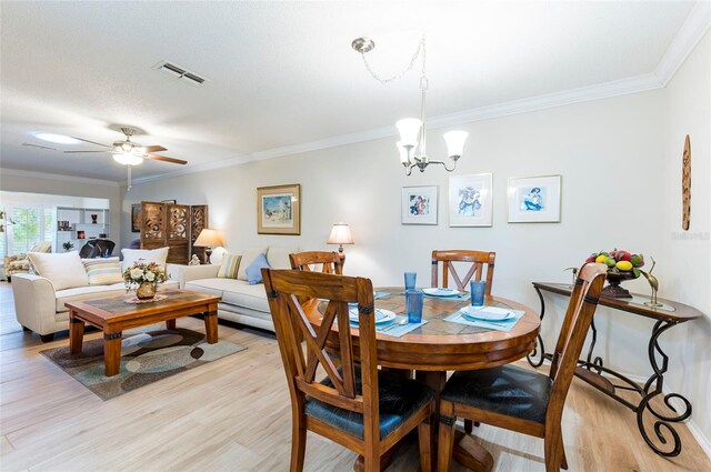 dining room with light wood-type flooring, ornamental molding, and ceiling fan with notable chandelier