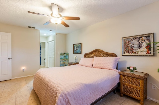 bedroom featuring light tile patterned floors, ceiling fan, a textured ceiling, and a closet