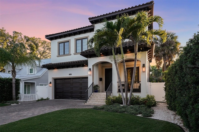 mediterranean / spanish-style house with a garage, a yard, and covered porch