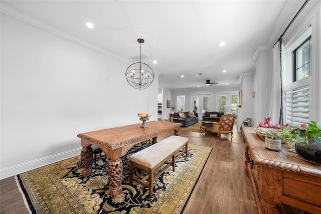 dining space featuring wood-type flooring, ceiling fan with notable chandelier, and ornamental molding