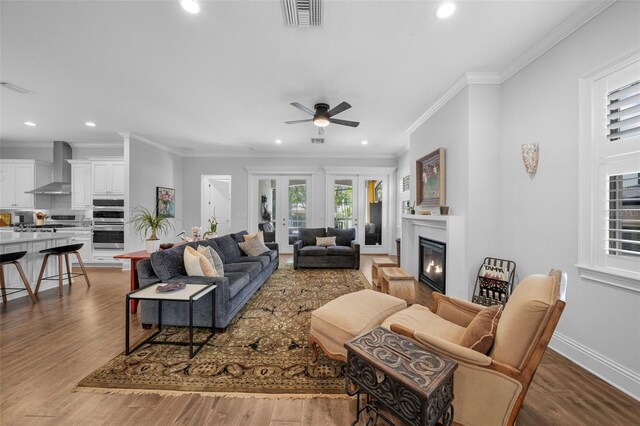 living room featuring dark hardwood / wood-style flooring, ceiling fan, and ornamental molding