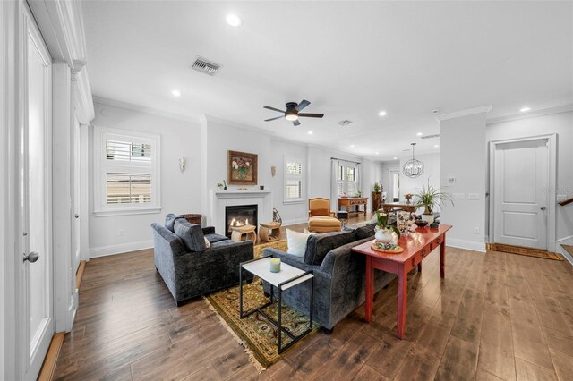 living room with hardwood / wood-style floors, ornamental molding, and ceiling fan with notable chandelier