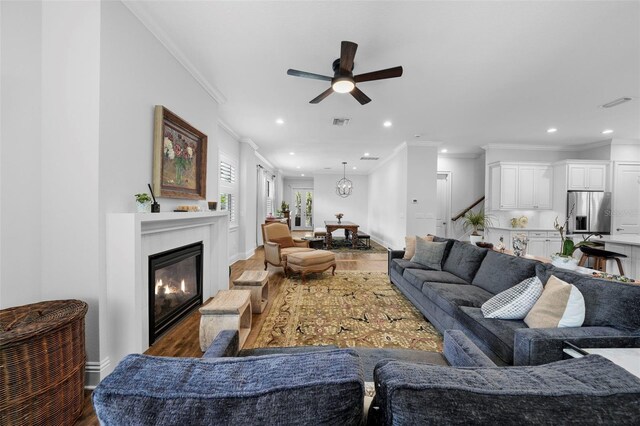 living room featuring hardwood / wood-style flooring, crown molding, and ceiling fan