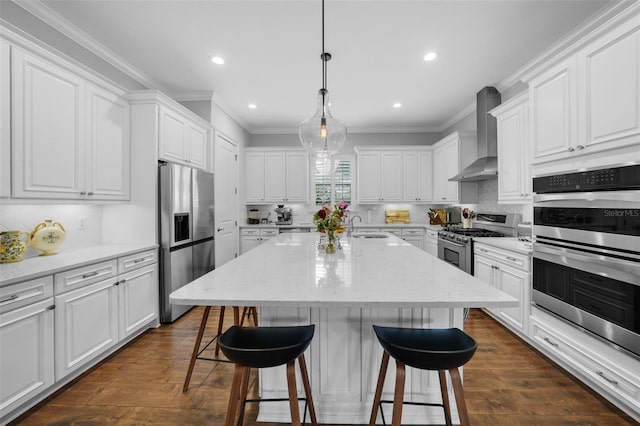 kitchen featuring stainless steel appliances, dark wood-type flooring, wall chimney range hood, and an island with sink