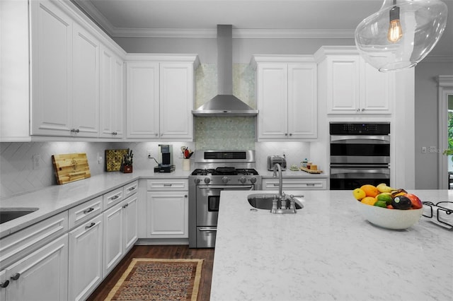 kitchen with white cabinets, stainless steel appliances, sink, and wall chimney range hood