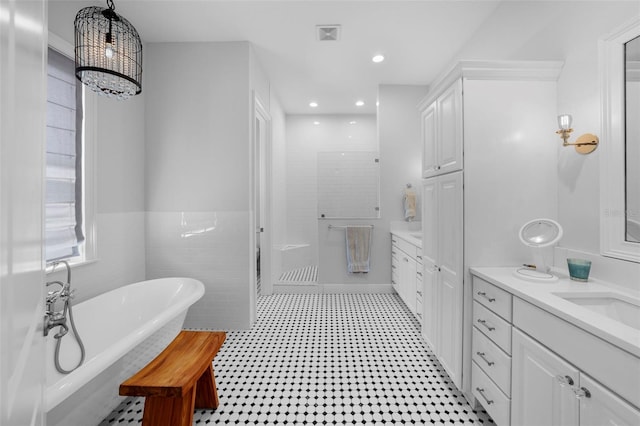 bathroom featuring a bath, vanity, and tile walls