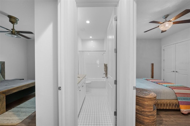 bedroom with ensuite bath, dark wood-type flooring, and ceiling fan