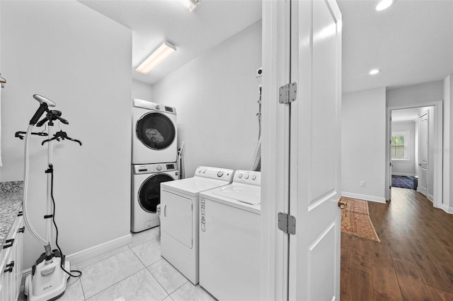 clothes washing area with light hardwood / wood-style floors and stacked washer / drying machine