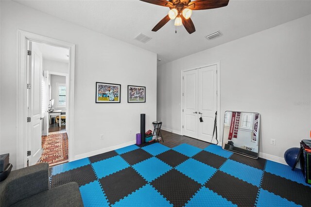 workout area featuring dark wood-type flooring and ceiling fan