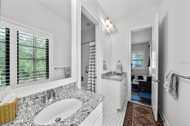 bathroom with vanity, a healthy amount of sunlight, and shower / bathtub combination with curtain