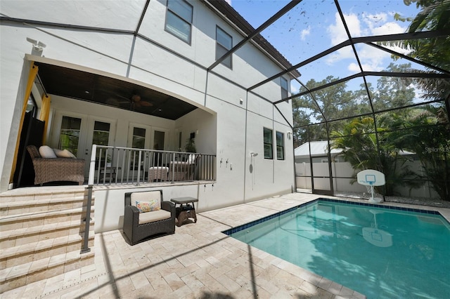 view of pool with glass enclosure, french doors, a patio, and ceiling fan