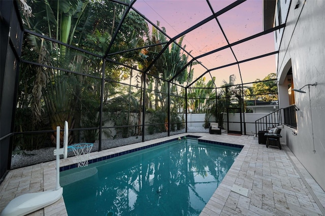 pool at dusk with a lanai and a patio