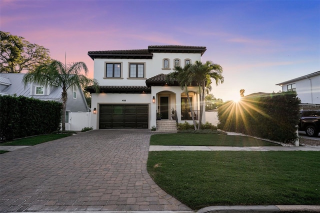 mediterranean / spanish-style home with a garage and a lawn