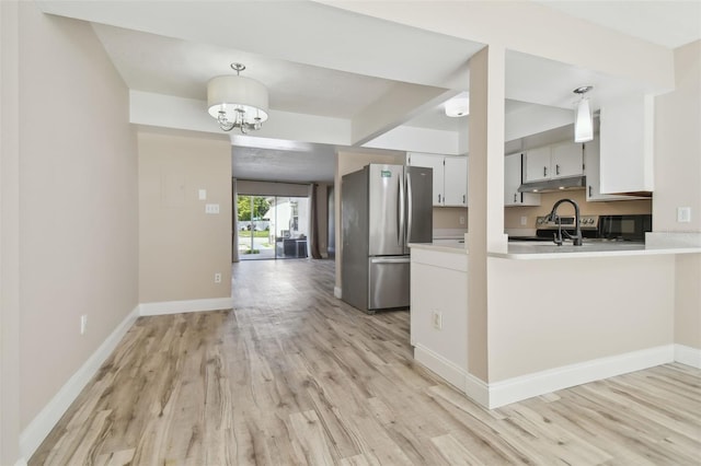 kitchen with pendant lighting, an inviting chandelier, light hardwood / wood-style floors, kitchen peninsula, and stainless steel refrigerator