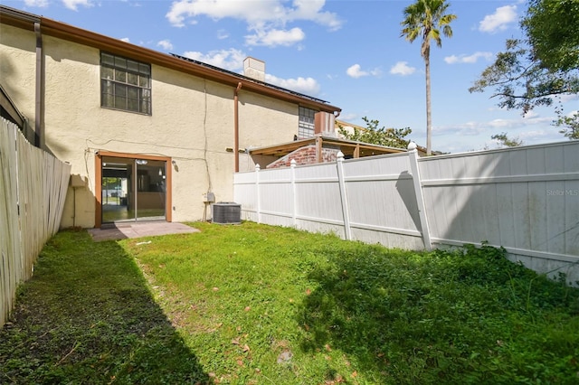 rear view of property with a yard and central air condition unit