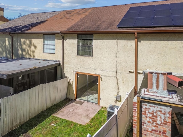 back of house with solar panels and central AC