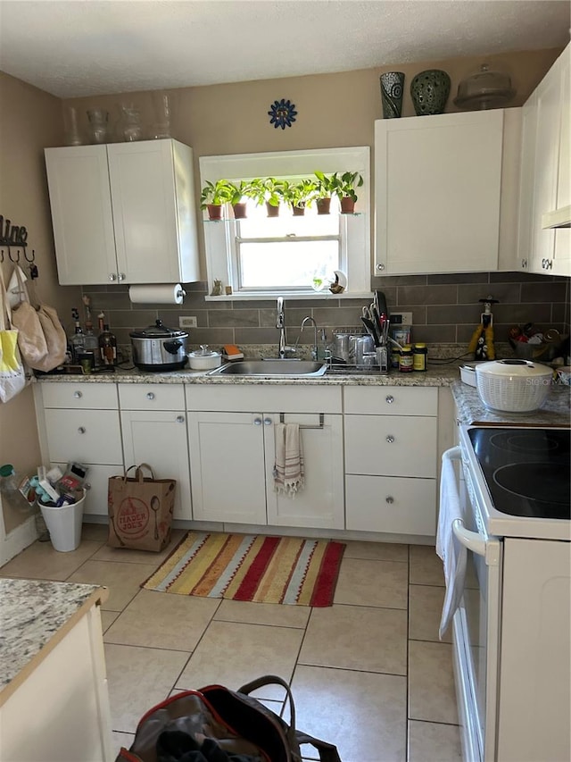 kitchen with white cabinets, sink, white electric stove, and tasteful backsplash