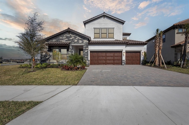 view of front of house featuring a garage, decorative driveway, a lawn, and stucco siding