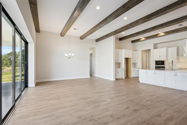 unfurnished living room featuring beam ceiling, a notable chandelier, light wood-style flooring, and baseboards