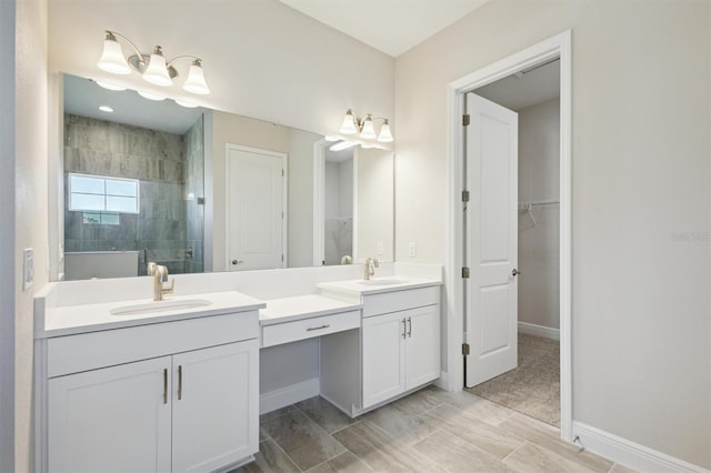 bathroom featuring a stall shower, a walk in closet, vanity, and baseboards