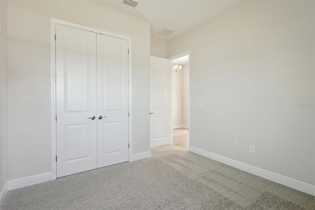 unfurnished bedroom featuring a closet, light colored carpet, visible vents, and baseboards