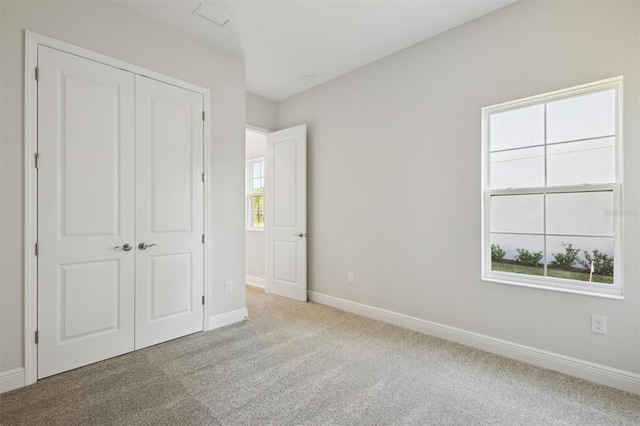 unfurnished bedroom featuring light carpet, a closet, visible vents, and baseboards