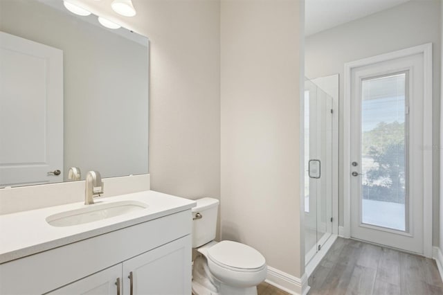 bathroom with baseboards, toilet, wood finished floors, vanity, and a shower stall