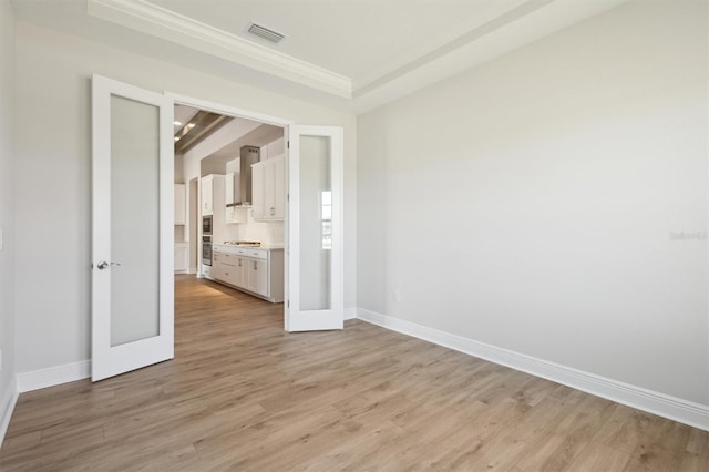 empty room featuring light wood-type flooring, french doors, visible vents, and baseboards