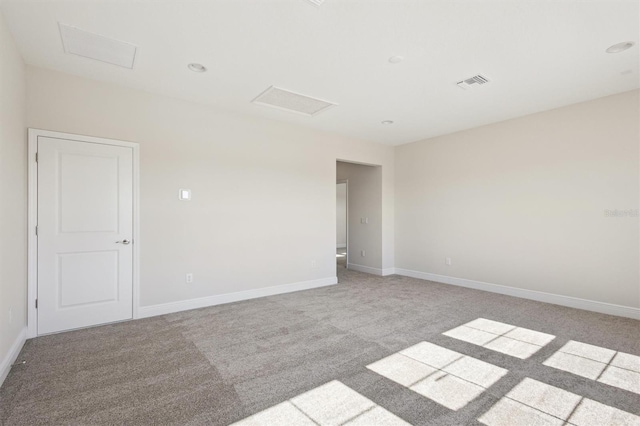 spare room featuring visible vents, light carpet, attic access, and baseboards