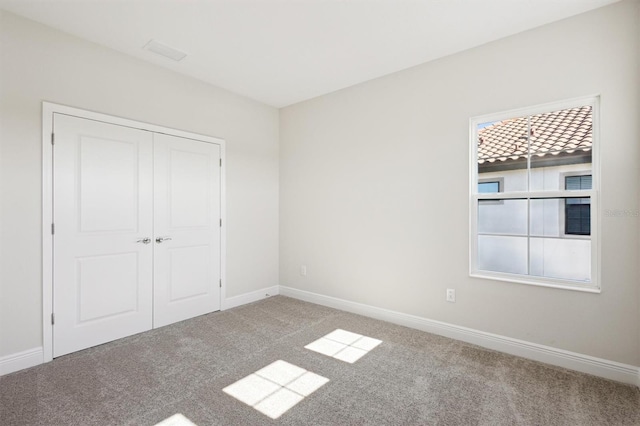 unfurnished bedroom with carpet floors, a closet, and baseboards