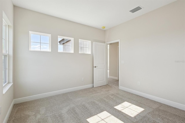 empty room with light carpet, visible vents, and baseboards