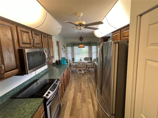 kitchen featuring ceiling fan, light hardwood / wood-style flooring, stainless steel appliances, and a textured ceiling