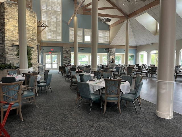 dining space featuring decorative columns, ceiling fan, dark hardwood / wood-style flooring, and high vaulted ceiling