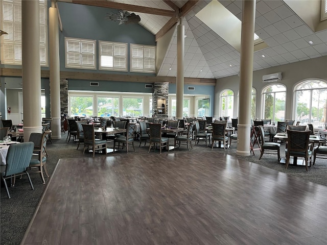 gym with a wall unit AC, dark hardwood / wood-style flooring, high vaulted ceiling, and decorative columns