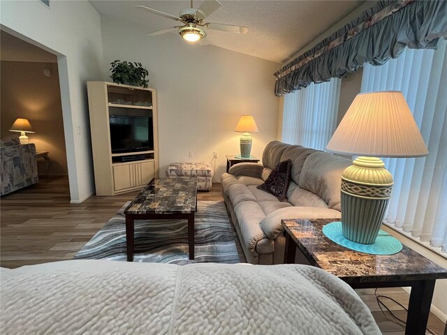 living room featuring hardwood / wood-style floors, ceiling fan, a textured ceiling, and vaulted ceiling