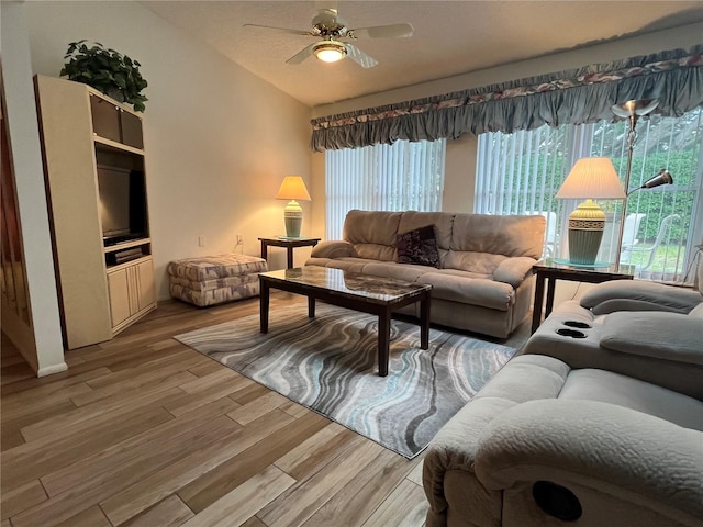 living room with ceiling fan, hardwood / wood-style floors, and vaulted ceiling