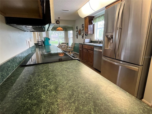 kitchen featuring ventilation hood, sink, a textured ceiling, and appliances with stainless steel finishes