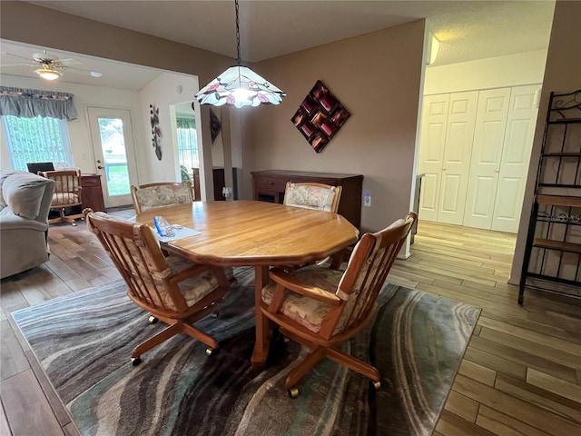 dining room with ceiling fan, wood-type flooring, and vaulted ceiling