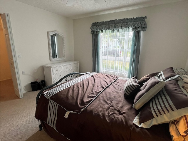 bedroom with a textured ceiling, carpet floors, and ceiling fan