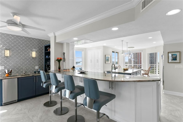 kitchen featuring pendant lighting, decorative backsplash, a breakfast bar area, and light stone counters