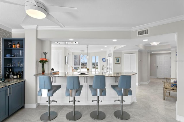 kitchen featuring pendant lighting, crown molding, a breakfast bar, and light stone countertops