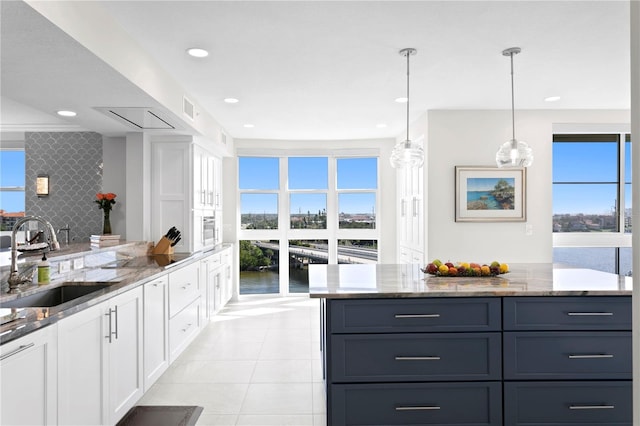 kitchen featuring plenty of natural light, sink, a water view, and white cabinetry