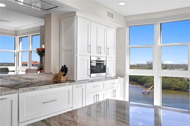 kitchen featuring white cabinets, oven, and ornamental molding