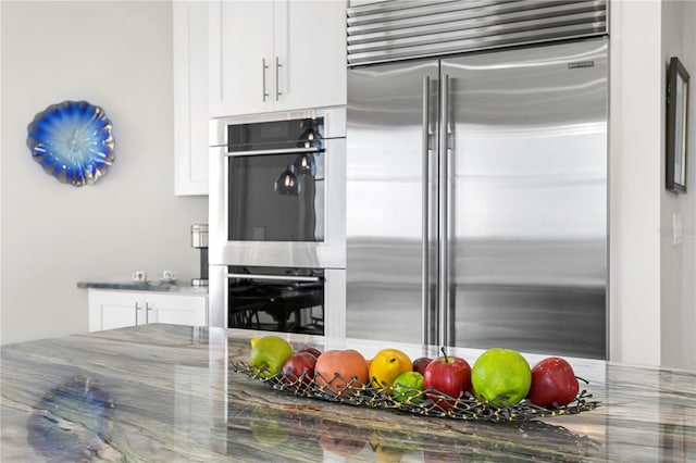 kitchen with dark stone counters, white cabinetry, and appliances with stainless steel finishes