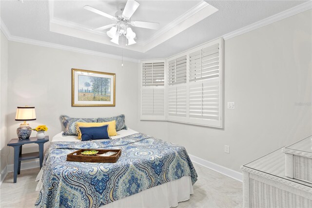 bedroom with ceiling fan, crown molding, and a tray ceiling