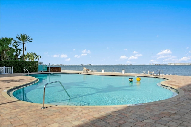 view of pool with a water view and a patio